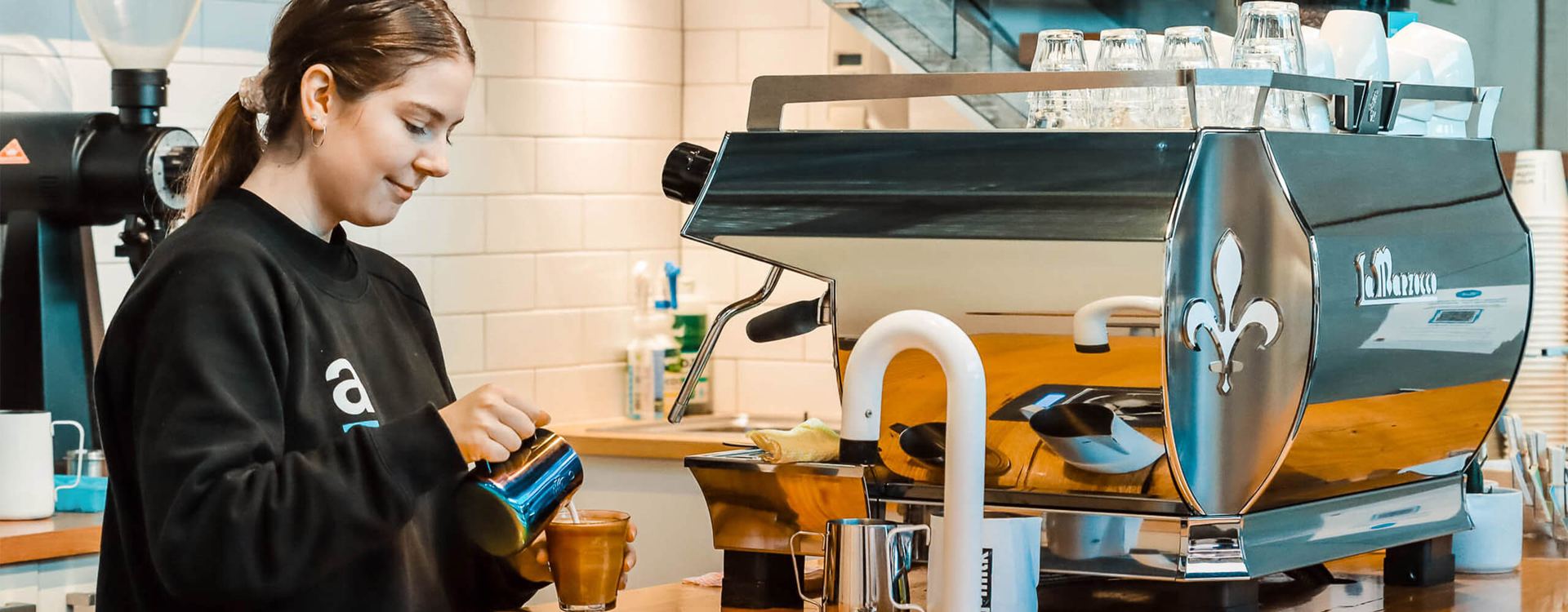 GB5 X w kolorze morskim na barze kawiarni, baristka spienia mleko