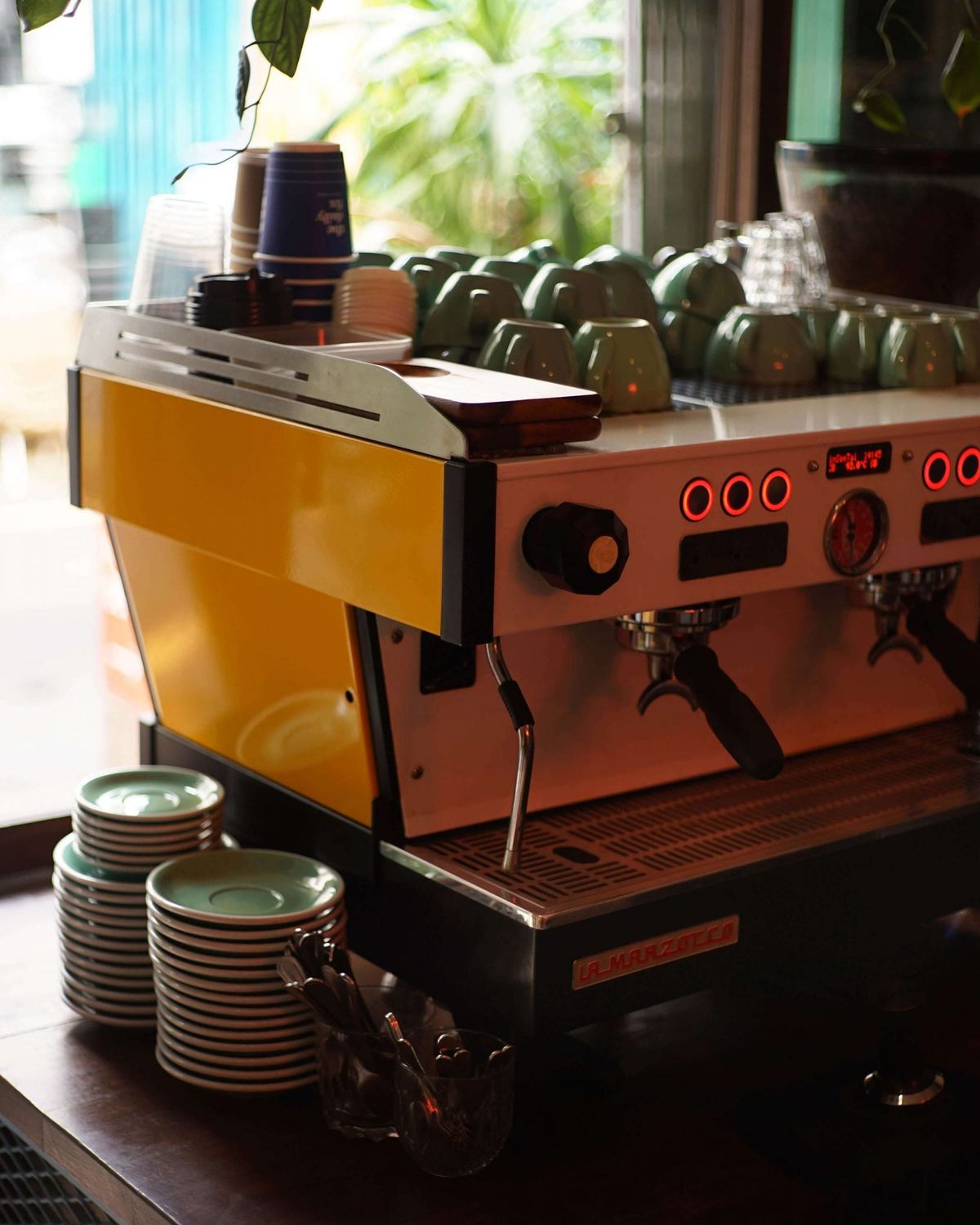 Żółty ekspres La Marzocco Linea PB w kawiarni, zbliżenie na grupy i filiżanki