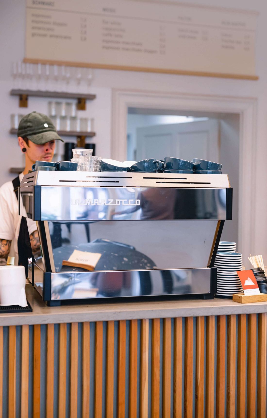 La Marzocco Linea PB X na drewnianym barze kawiarni, za nią barista